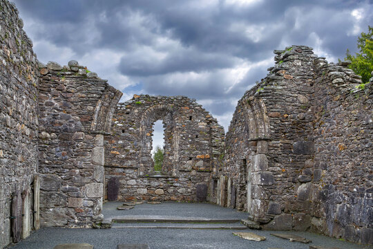 Historic ruins of the medieval cathedral in Glendalough, Ireland. Ancient stone architecture stands under a cloudy daylight sky