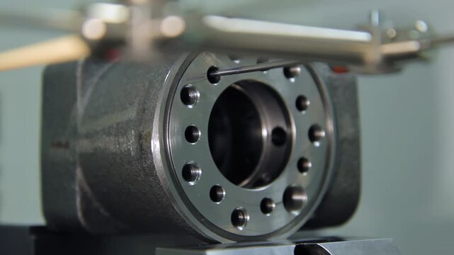 Metal part quality control close up. CMM probe checking threaded holes factory.