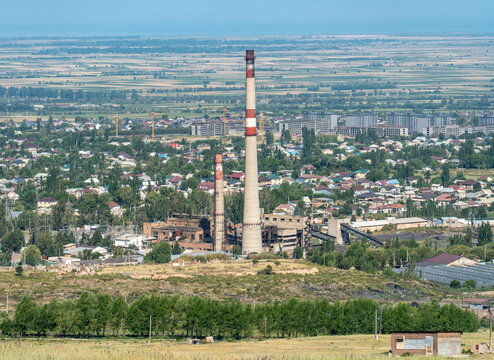 High angle view of the Karakol heat generation plant with two tall chimneys, new apartment blocks and solar panels on a summer day, Kyrgyzstan.