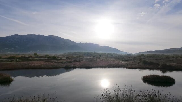 Lateral Wetland View with Sun and Mountain Reflections