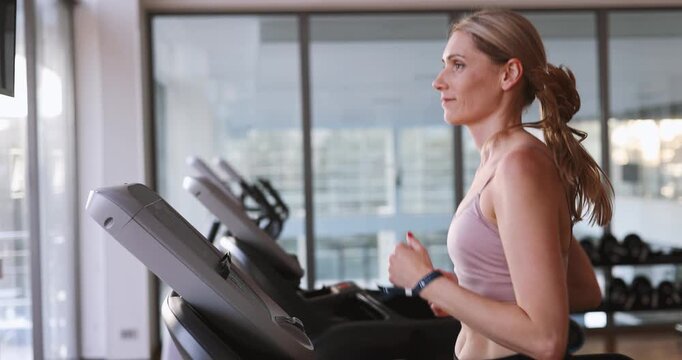 Determined woman running on a treadmill at the heath club gym .Cardio workout