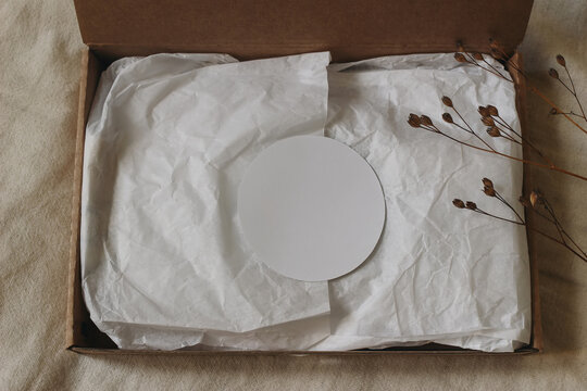 Minimal Round Blank Sticker Label Mockup. White Crumpled Tissue Paper, Open Kraft Cardboard Gift Box. Eco Packaging, Sustainable Branding, Natural Linen Background, Dried Flowers, Flat Lay, topview