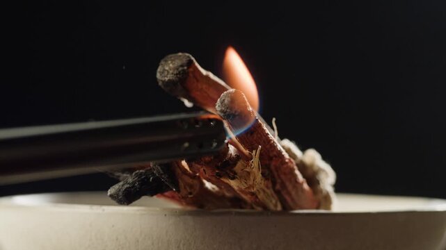 Person holding Palo Santo wood stick in hand, aromatic Palo Santo burning on black background, smoke spreading around, slow motion video clip, high quality 4k close up footage