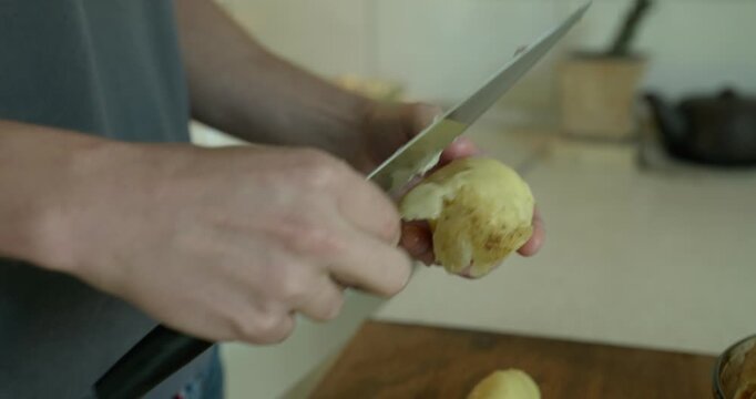 Close-up male hands peel boiled potato with knife. 4K 10-bit