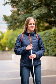 Visually impaired woman walking with a white cane in the city