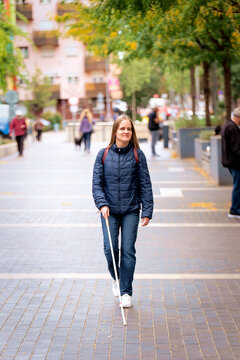 Visually impaired woman walking with a white cane in the city
