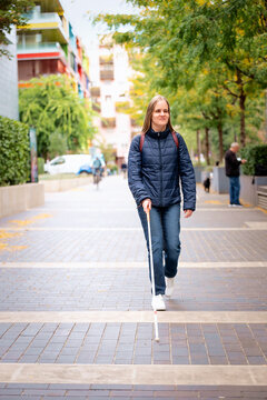 Visually impaired woman walking with a white cane in the city