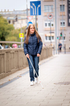 Visually impaired woman walking with a white cane in the city