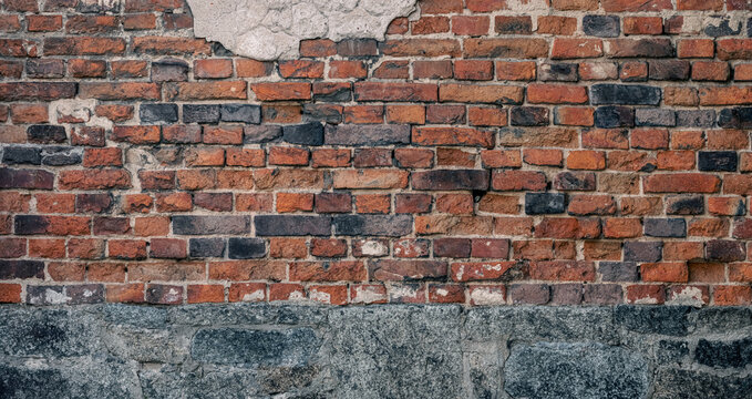 Weathered red brick wall, historic stone foundation, textured backdrop