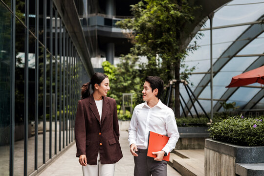 Coworkers walk and talk outside a modern office building