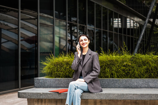 Businesswoman talks on her phone outside a modern office