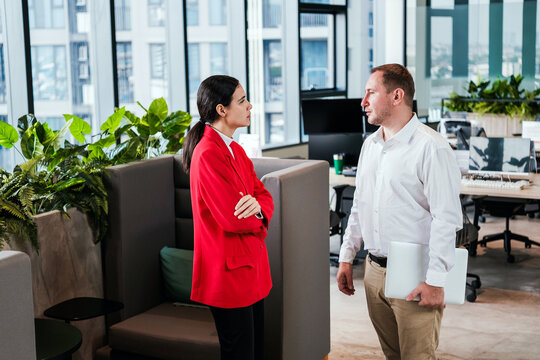 Coworkers discuss work beside lounge seating in a modern office