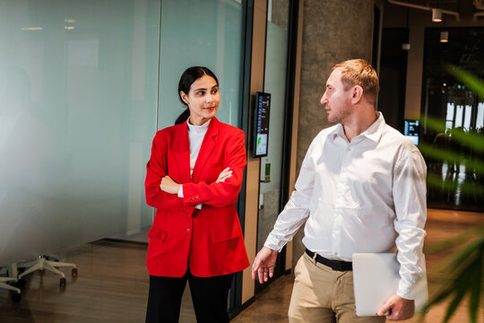 Business colleagues talk in a modern office hallway