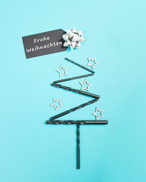 Christmas tree made from drill, silver stars and a merry christmas sign in german language, holiday greeting card, banner or background for handyman, craftsman or repairman, advent winter season
