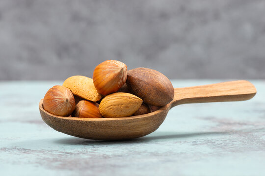 Nuts mixture, hazelnuts, peanuts and almonds in a wooden shovel, healthy food, nutrition, ingredients for baking, protein and antioxidants