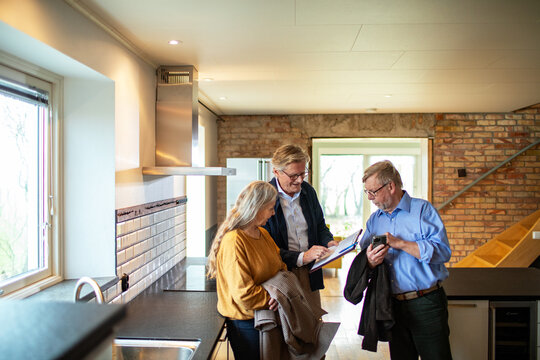 Real estate agent reviewing paperwork with senior couple in kitchen