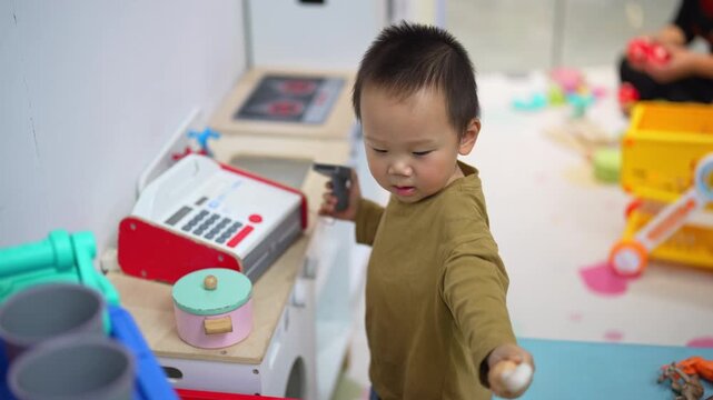 Boy playing shop with a toy cash register