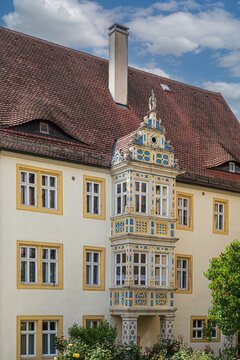 Dekanatshaus in Rothenburg ob der Tauber, Germany, featuring a richly decorated Renaissance bay window, colorful carvings, red tiled roof, and traditional dormers near St. James&rsquo;s Church.