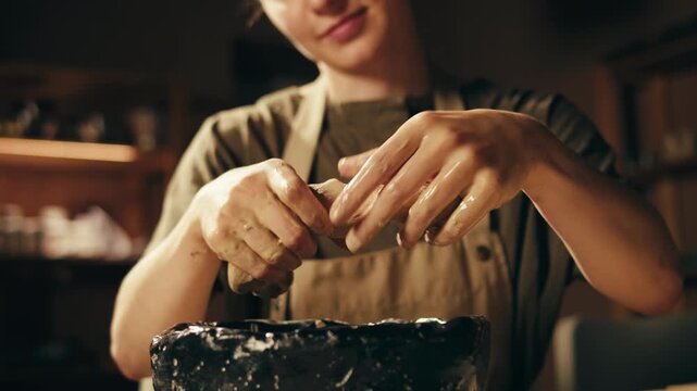 Woman potter works with clay on master class in studio. Working process in ceramic workshop. Potter making vase on pottery wheel. Handmade concept. 