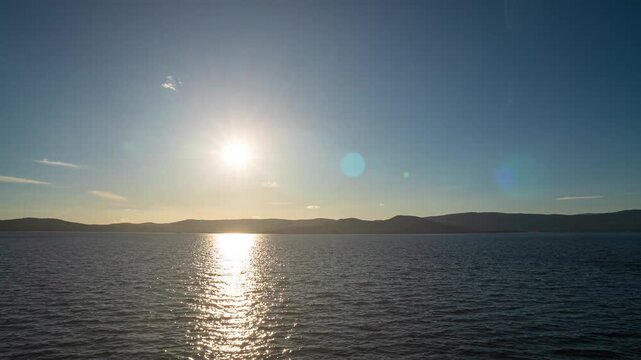 Timelapse of beautiful blue sky with clouds on bright sunny day Sun rays emerge through the clouds. Beautiful evening sky over the lake
