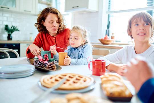 Mother and children sharing breakfast in a bright home kitchen, stirring drinks, eating waffles, and enjoying warm family time together