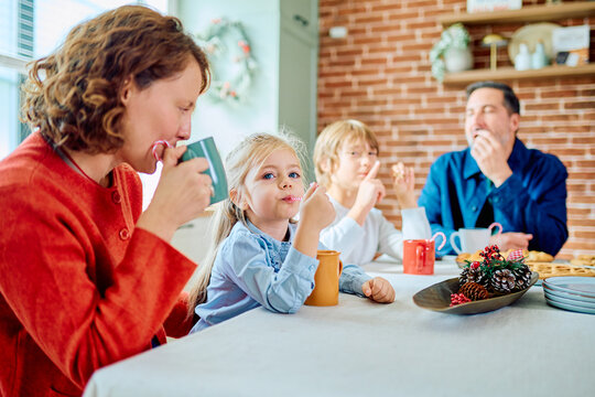 Family gathering around a kitchen table for a festive holiday breakfast, sipping drinks and sharing food together