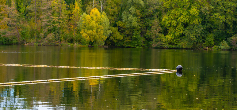 Den See an der Badeanstalt im Volkspark Jungfernheide im Herbst, im Bild sind die Schwimmleinen mit Boje Abgrenzungen vom See zum Schwimmbad zu erkennen, Berlin-Charlottenburg, Deutschland