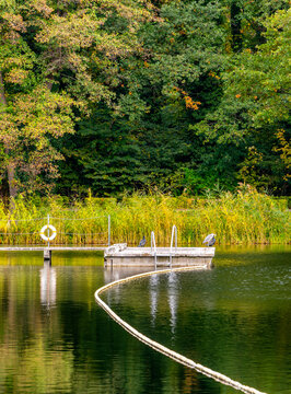 Den See an der Badeanstalt im Volkspark Jungfernheide im Herbst, im Bild sind die Schwimmleinen mit Boje Abgrenzungen vom See zum Schwimmbad zu erkennen, Berlin-Charlottenburg, Deutschland
