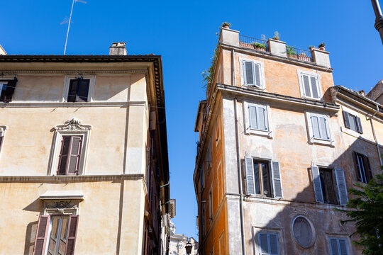 Historic ochre buildings with wooden shutters against a clear blue sky in the centre of Rome, Italy