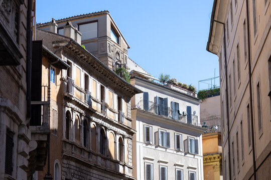 Historic Renaissance buildings with shuttered windows and rooftop gardens under blue sky in Rome, Italy