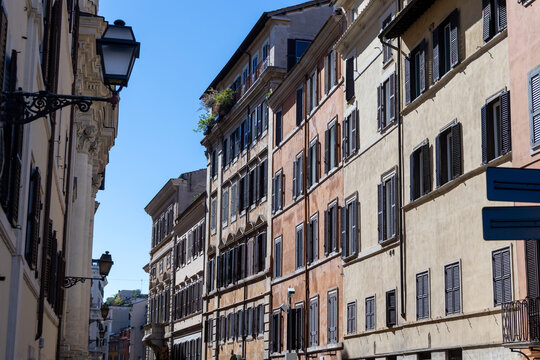 Historic ochre and terracotta building facades with wooden shutters on a street in central Rome, Italy