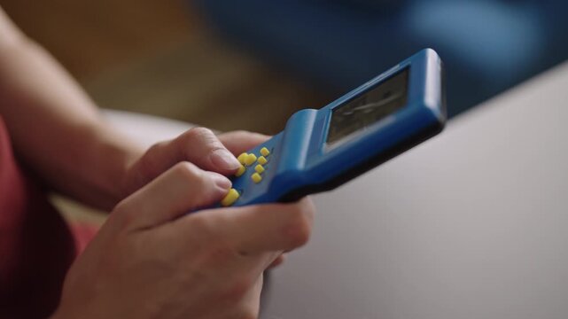 Female hands pressing buttons on old school electronic game from nineties, enjoying nostalgic moment of entertainment and playing classic vintage puzzle game, close-up, slow motion.
