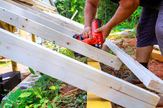 Contractor is working on building project using nail gun to secure wooden beams.