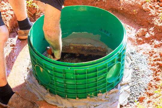 Contractor is digging adjusting green septic tank structure in concrete, securing it.