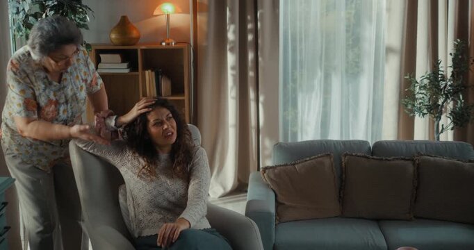 Elderly mother and her adult daughter have an emotional argument at home, expressing disagreement, tension and unresolved family problems.