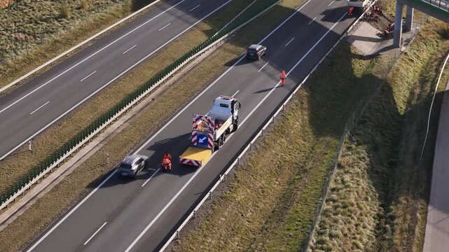 Road maintenance truck blocking a highway lane while workers perform service operations