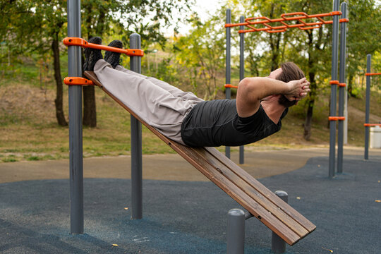 Man perform abdominal exercise on outdoor fitness bench