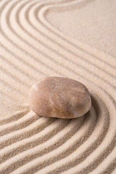 Zen stone on raked sand with calming circular pattern