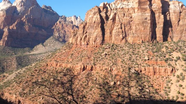Rugged sandstone peaks rising above desert canyons under bright blue skies, showing magnificent red rock geology and natural wilderness scenery during sunny daylight. Driving in Zion National park