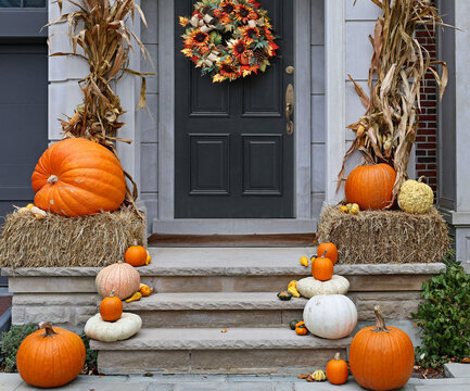 Front door of house with autumn decorations, pumpkins and straw bales
