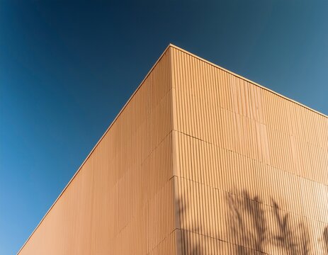 corner of modern beige building exterior wall against blue sky minimalist architectural detail with sharp contrast of light and deep shadow geometric background for abstract design