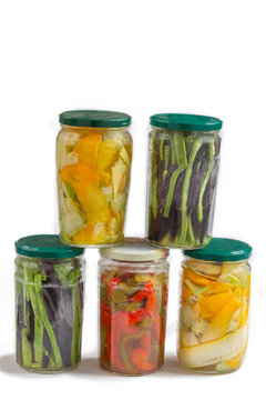 Five jars filled with pickled vegetables are stacked together. The jars show a variety of colors and types of vegetables, including carrots and peppers.