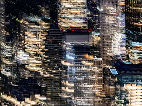 Abstract night view of Midtown Manhattan office towers with blurred lit windows and streaks of light created by camera movement, New York City.