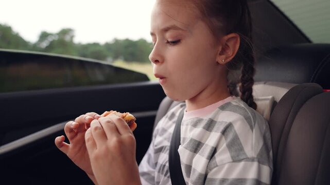 little girl child eating burger in car, happy person, Happy childhood with burgers, Travel food essentials for families, Kid-friendly car meals, Snack time fun for young travelers, Nostalgic road trip