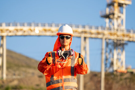 Industrial worker giving thumbs up, with respirator around his neck, at a construction site