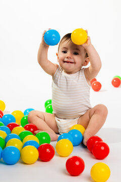 Happy baby playing with colorful plastic balls