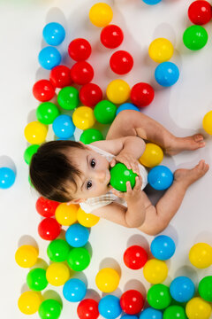 Baby playing with colorful plastic balls on floor