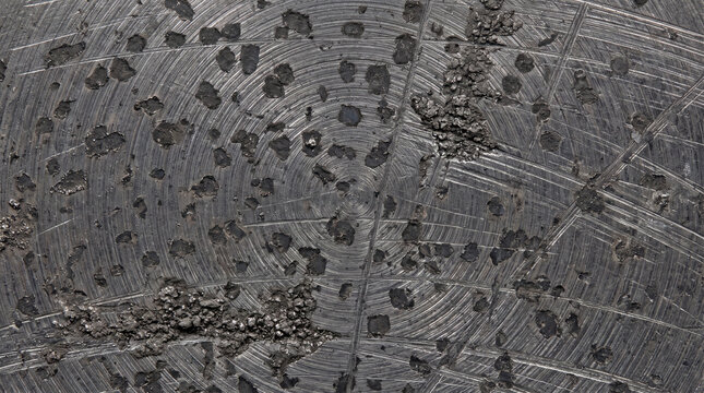 Circular machined metal surface with rough textured friction patterns and dark grey finish