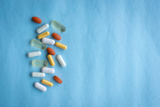 Assorted Colorful Pills and Capsules on Blue Background, copy space. Healthcare and medical concept.
