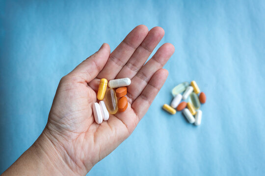 Person Holding Assorted Pills and Supplements. Healthcare and medicine concept.